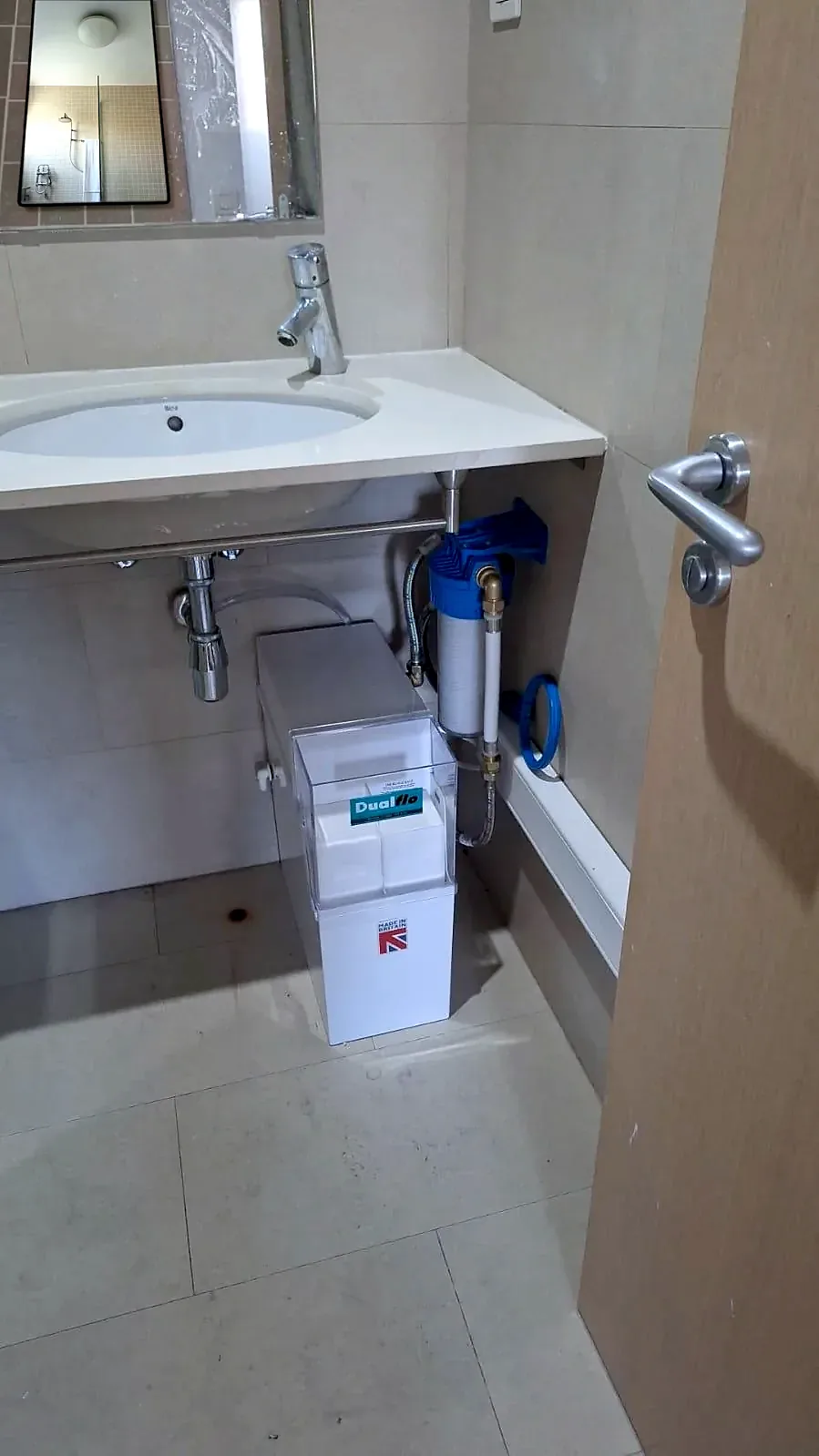 Descalcificador Dualflo amb filtre d'entrada instal·lat sota el lavabo d'un bany