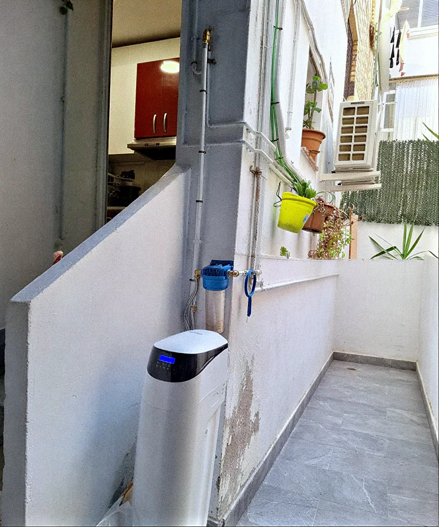 Descalcificador VD instal·lat en un pati exterior, amb filtre d'entrada a la paret